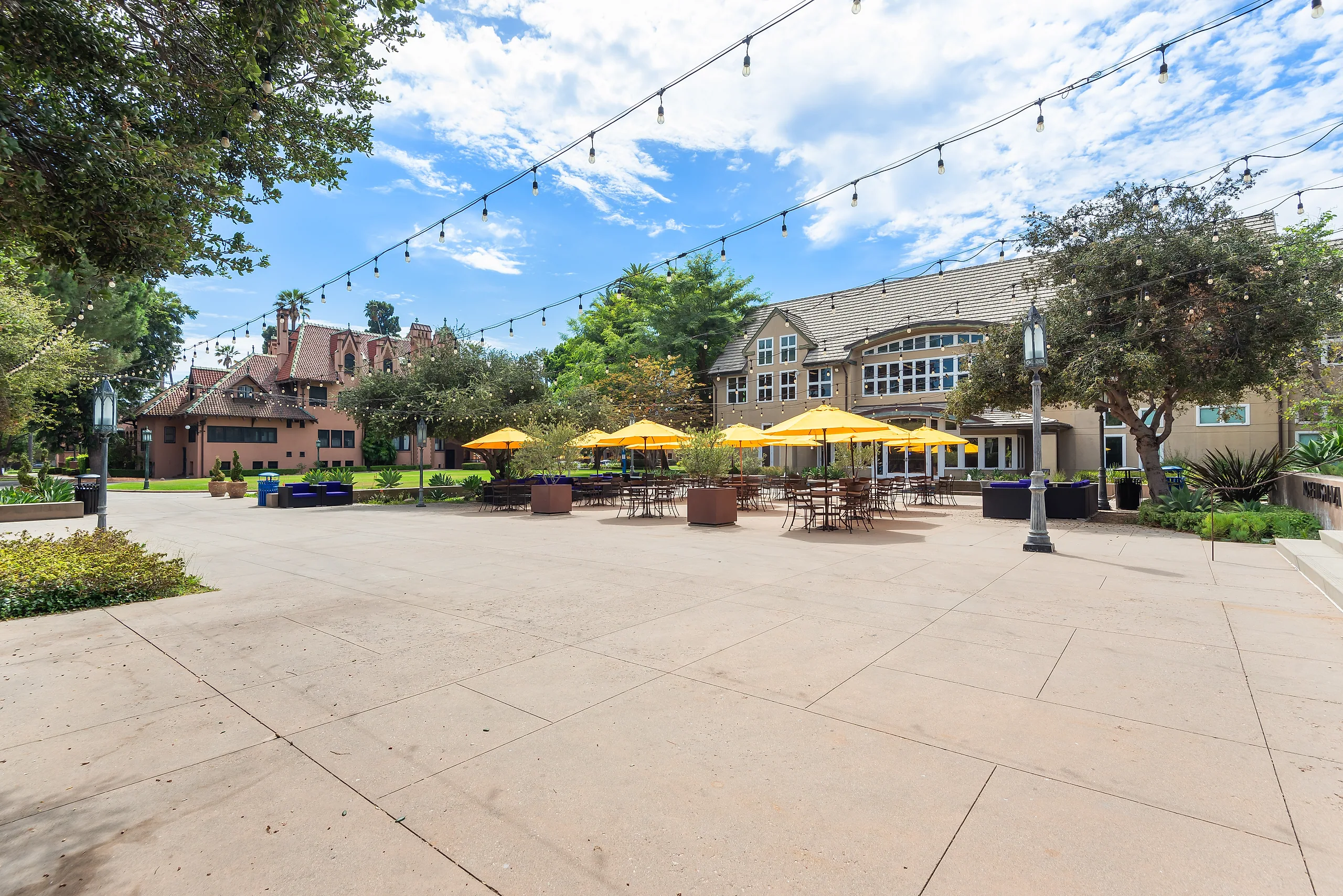 Umbrella-shaded tables and string lights on Rose Hills Plaza at Doheny Campus