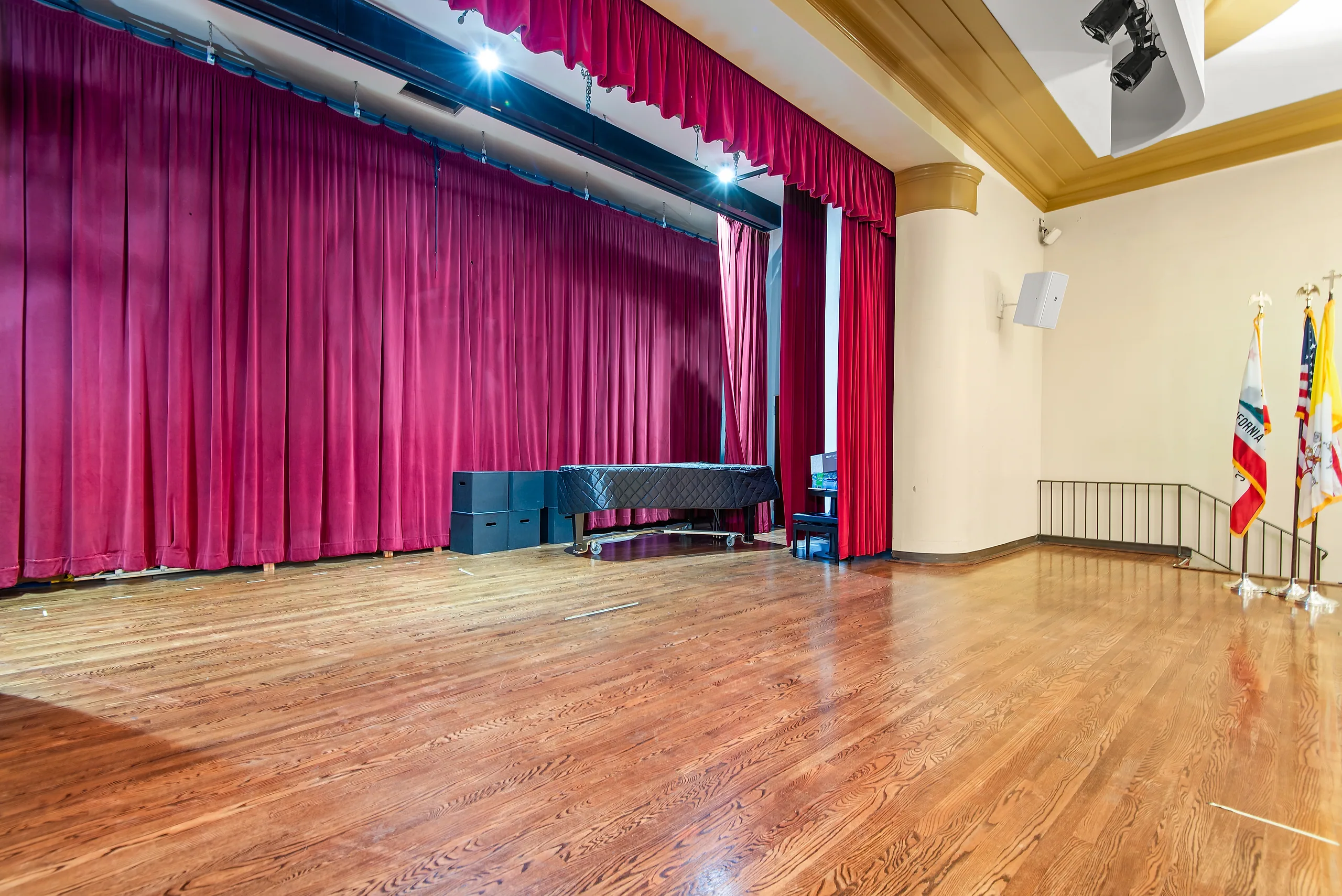 Stage with grand piano and red curtain inside Hannon Theater at Chalon Campus